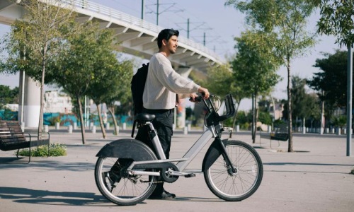 A man walking with a city bike.